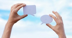 Two hands holding up speech bubble-shaped pieces of paper